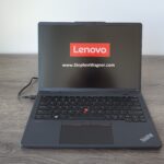 A Lenovo Thinkpad X13s on desk powered on with Red Lenovo logo